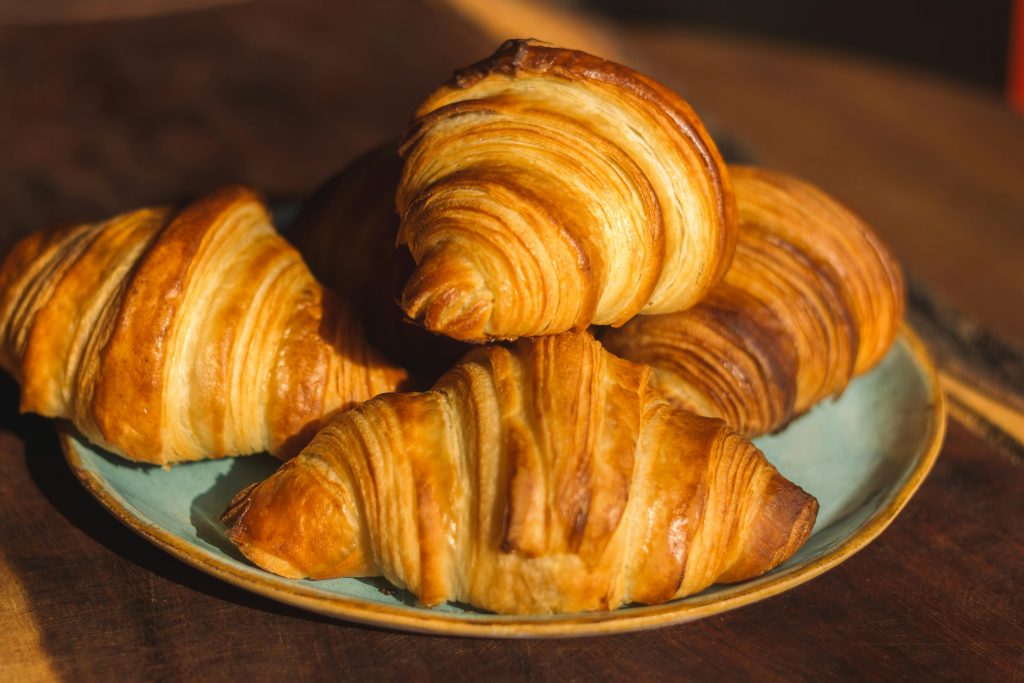Close-up of freshly baked golden croissants on a plate, perfect for breakfast imagery.